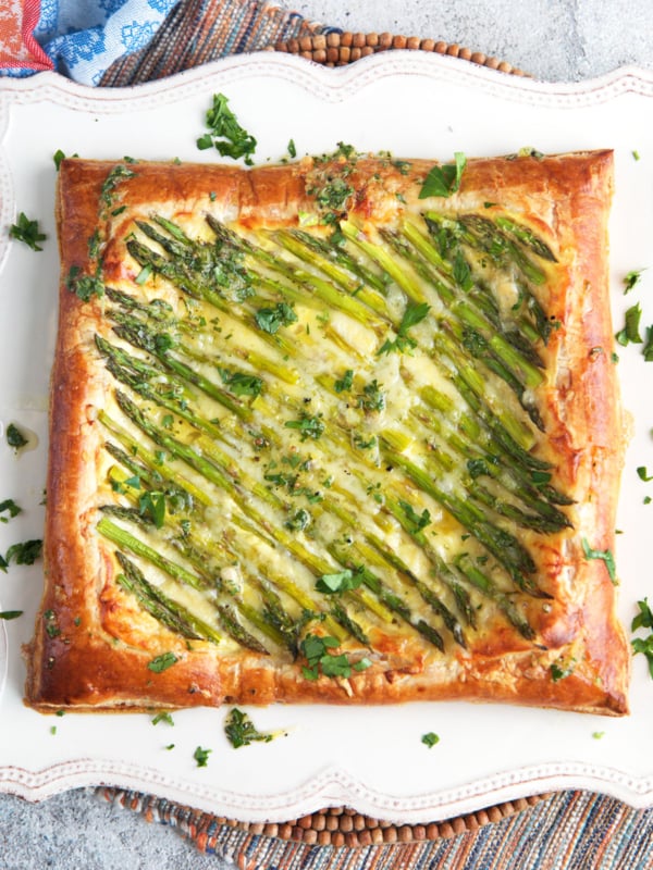 Asparagus puff pastry tart on a white square serving platter.