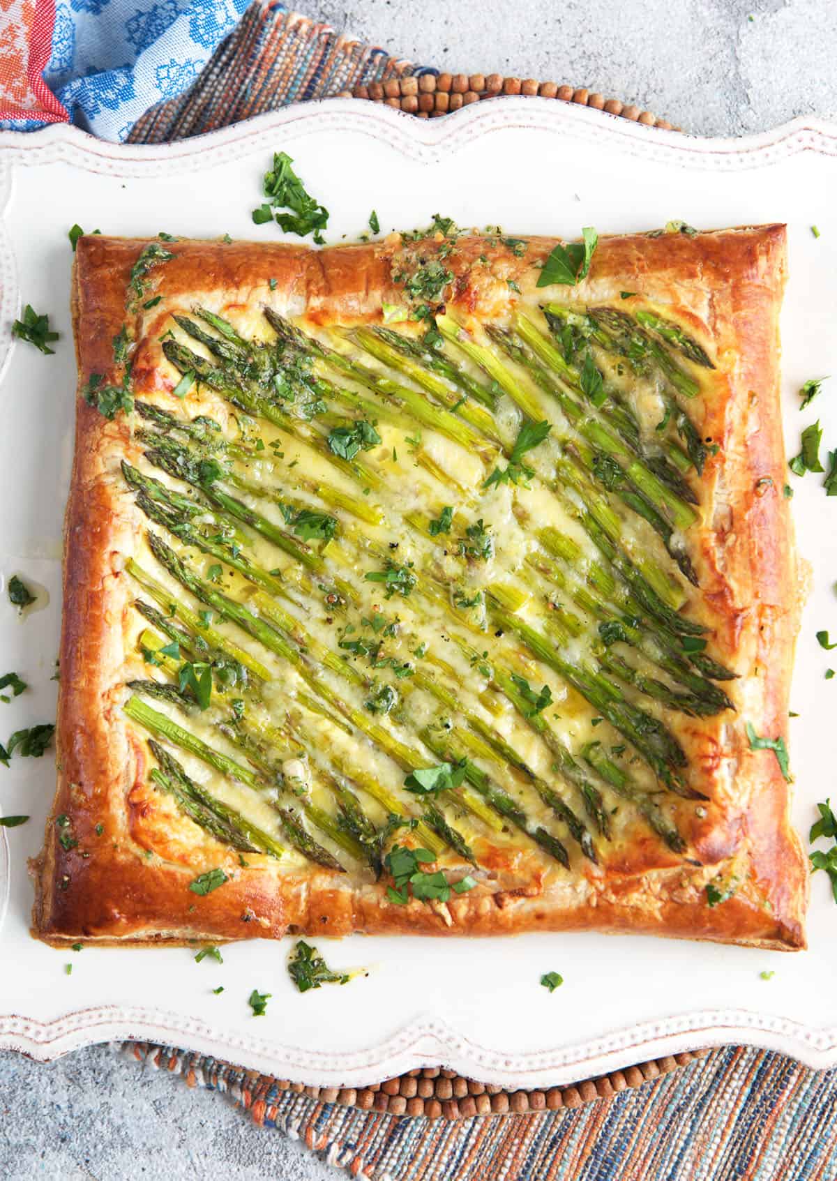 Asparagus puff pastry tart on a white square serving platter.