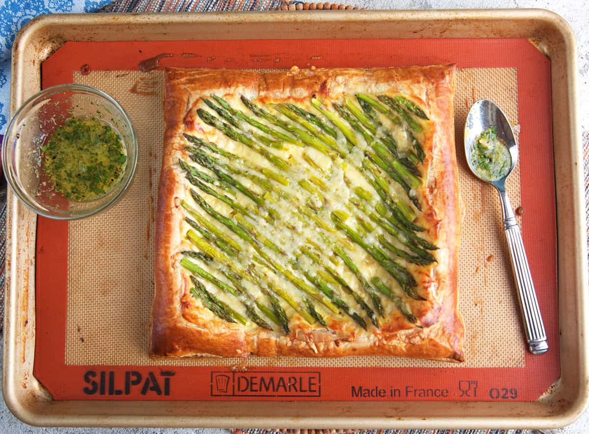 Asparagus tart after being baked on a baking sheet with herb butter to be drizzled on top