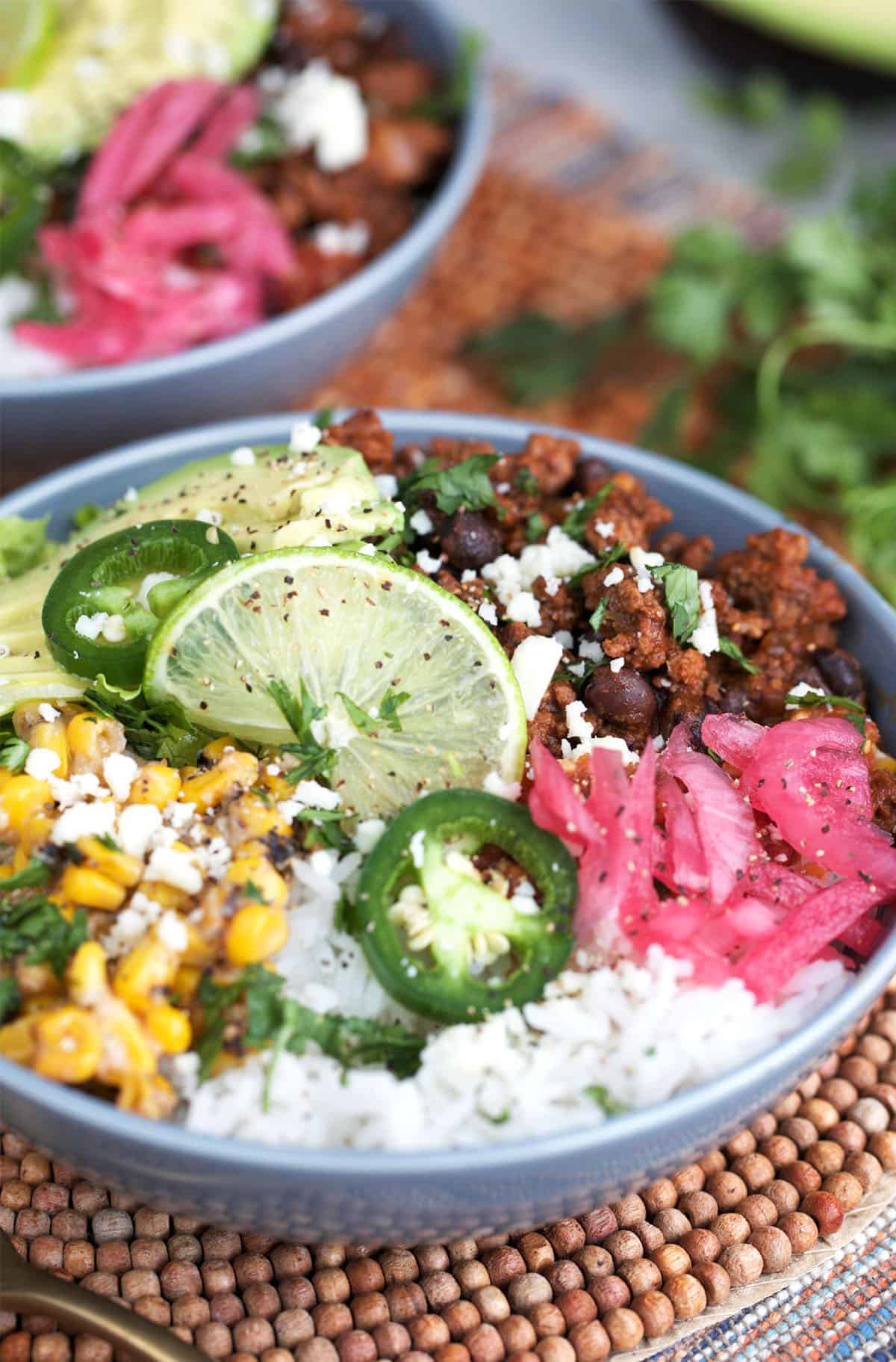 Ground beef taco bowls with rice, corn and lime on top.