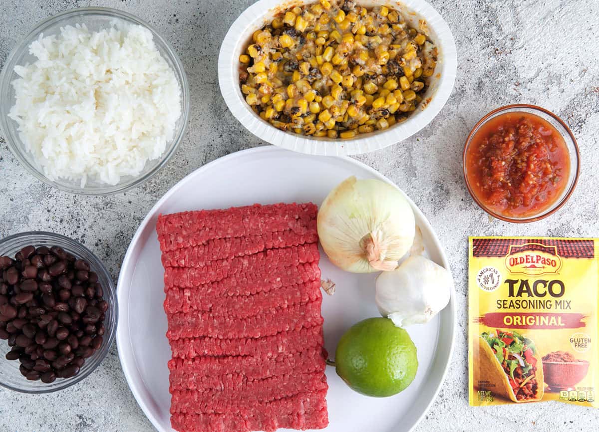 Ingredients for Taco Bowls on a plate with bowls of toppings.
