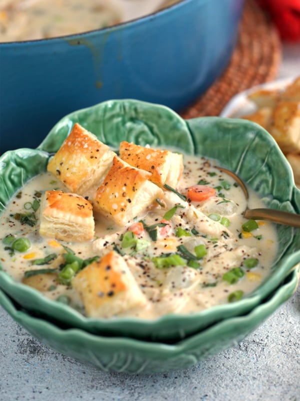 Chicken Pot Pie soup in a cabbage ware bowl with a copper spoon topped with croutons.