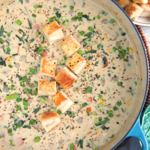 Chicken Pot Pie Soup in a blue dutch oven topped with puff pastry croutons