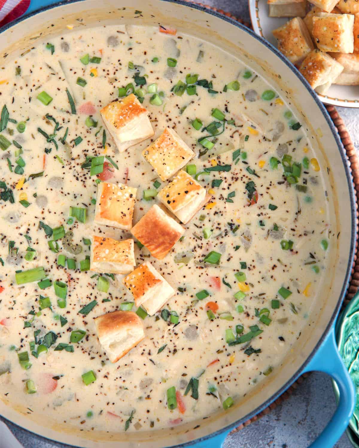 Chicken Pot Pie Soup in a blue dutch oven topped with puff pastry croutons