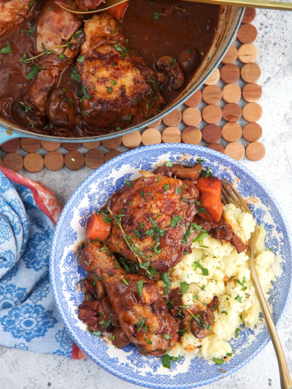 Coq au vin served over mashed potatoes with a gold fork.