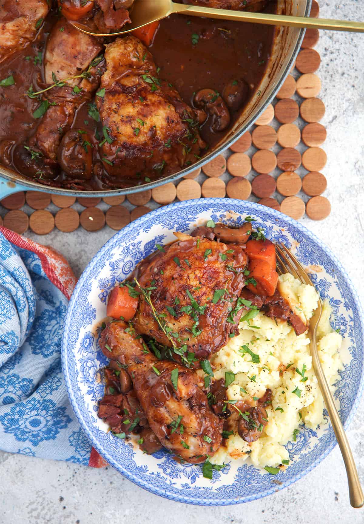 Coq au vin served over mashed potatoes with a gold fork.