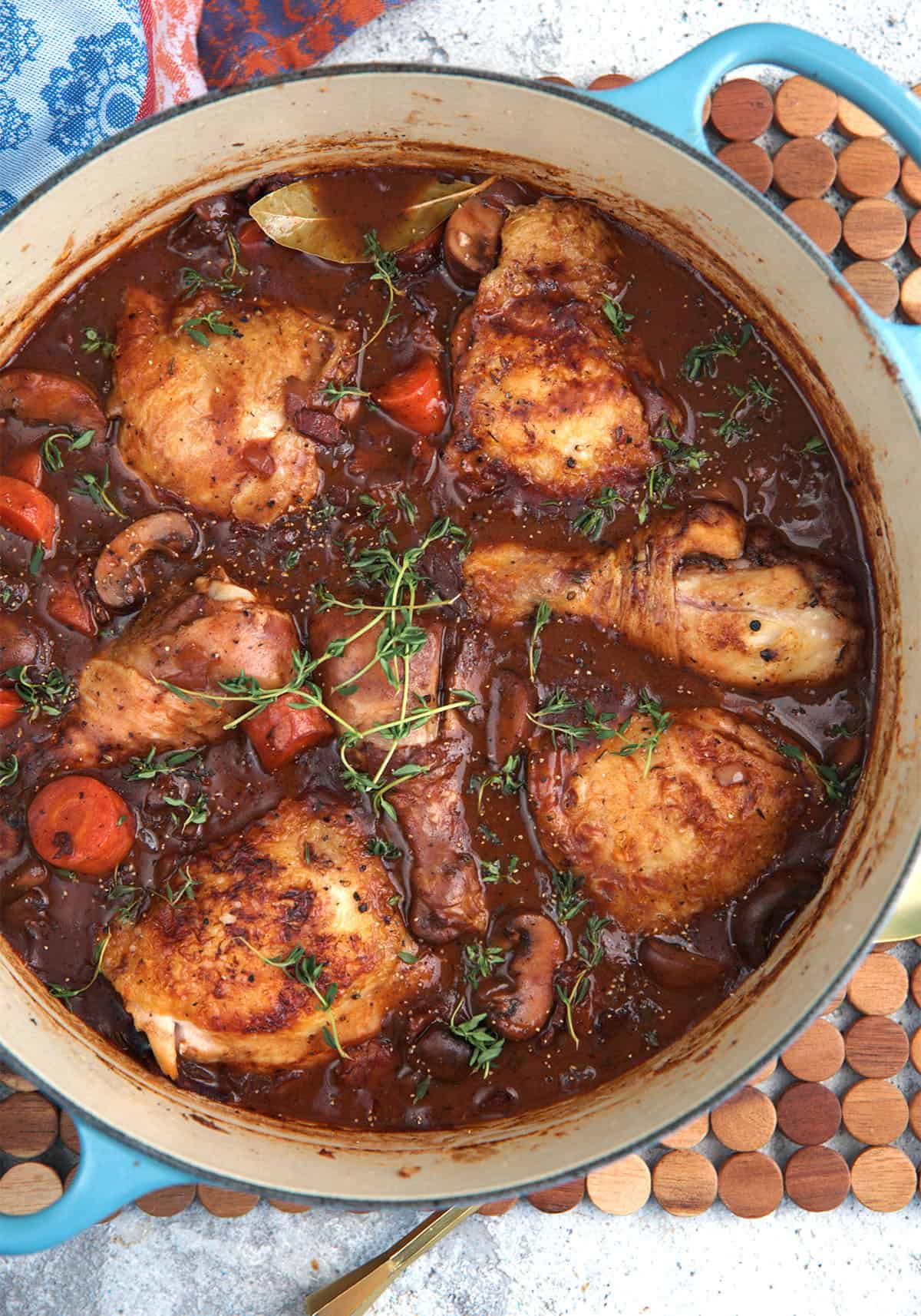 Coq au vin in a blue le creuset dutch oven.