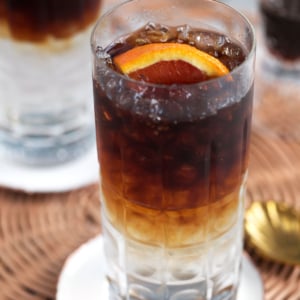 Espresso tonic in a crystal collins glass and a slice of orange on top