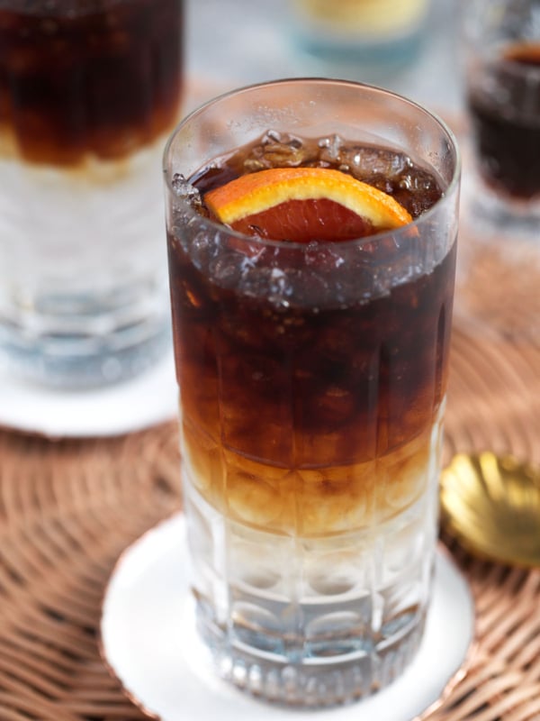 Espresso tonic in a crystal collins glass and a slice of orange on top