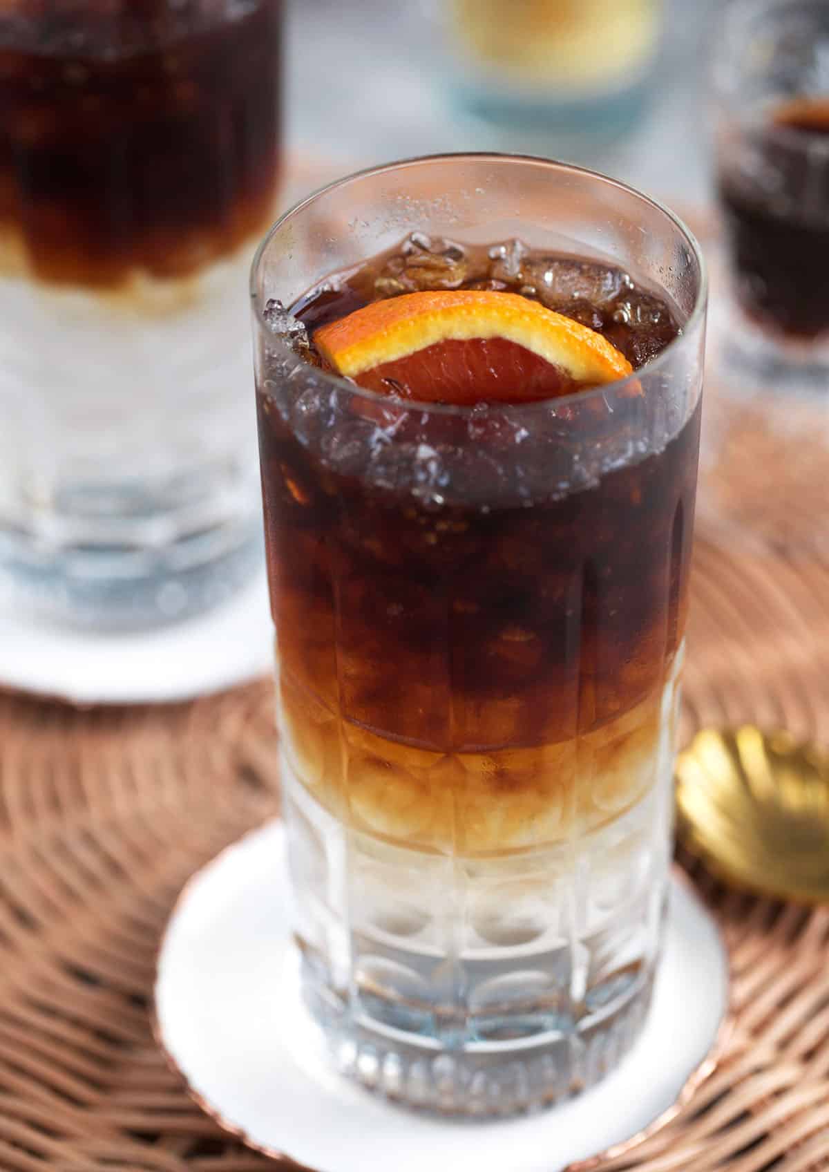 Espresso tonic in a crystal collins glass and a slice of orange on top