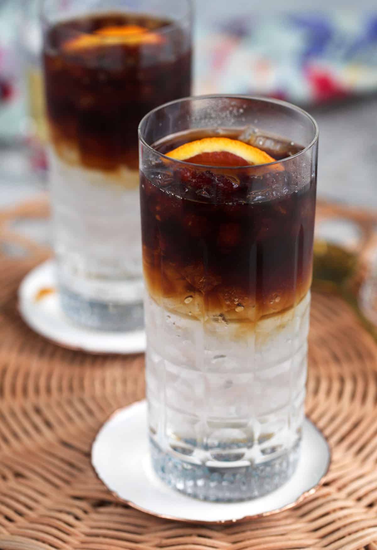 layered espresso tonic in a glass with a orange slice on top