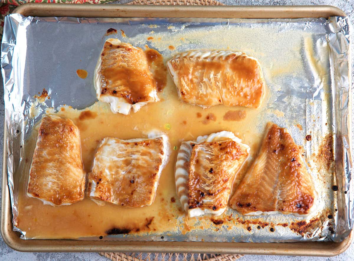 Miso glazed cod on a foil lined baking sheet after being baked.