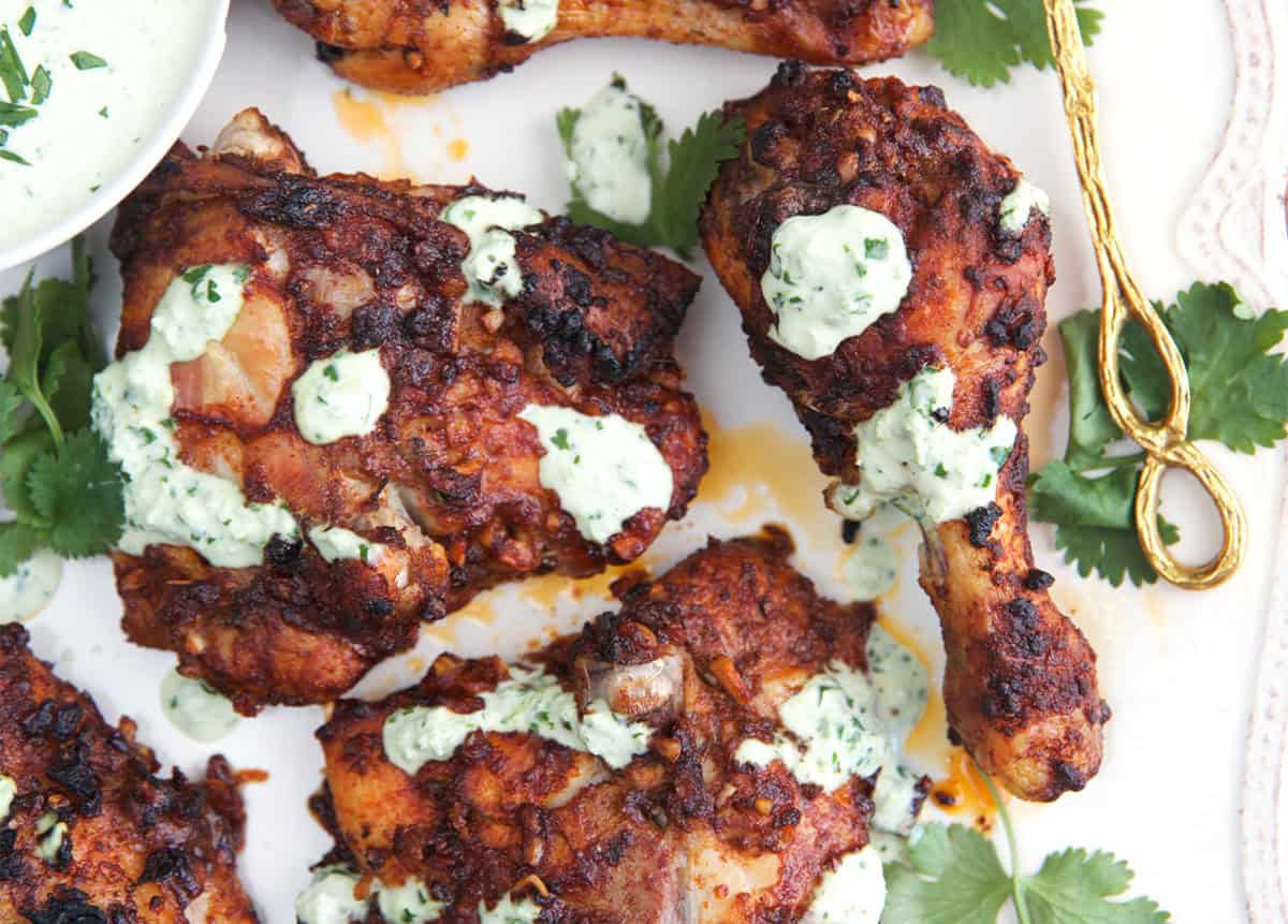 Peruvian chicken on a platter ready to serve with creamy green sauce.