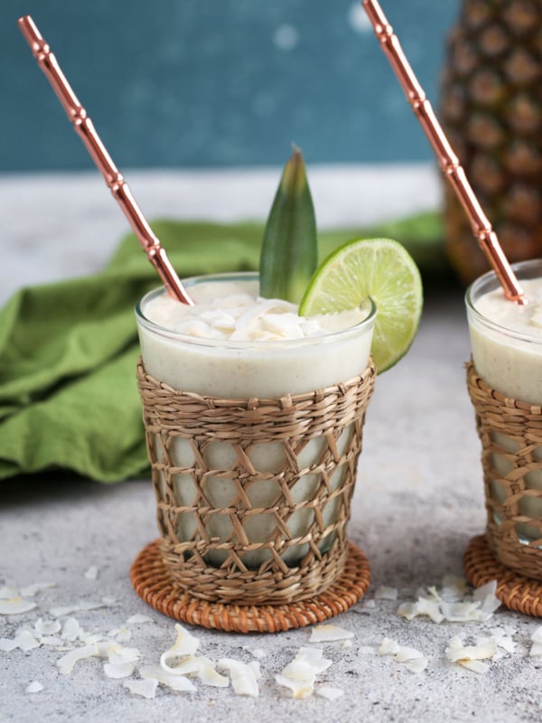 Pineapple smoothies with a straw and coconut flakes.