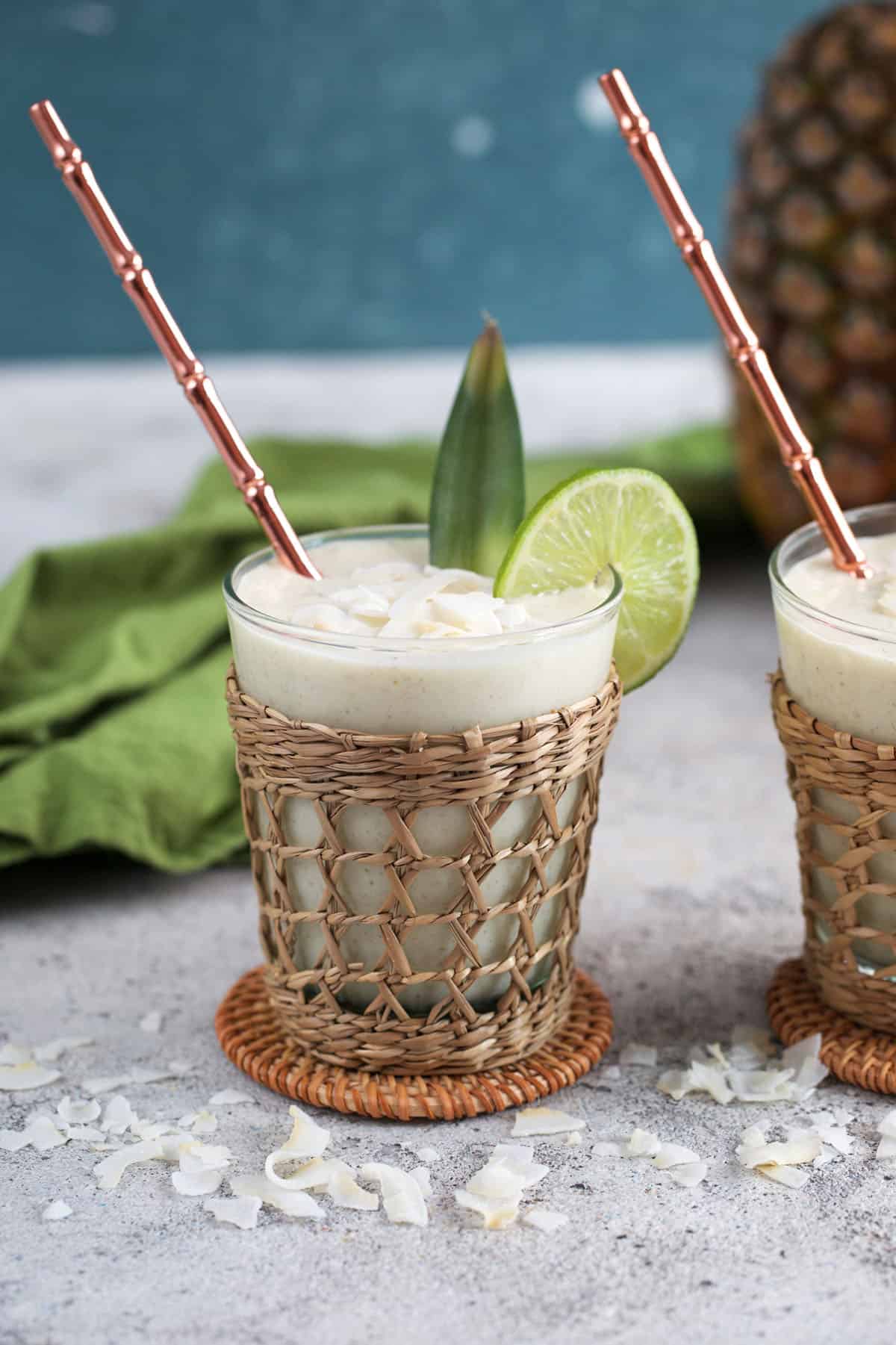Pineapple smoothies with a straw and coconut flakes.