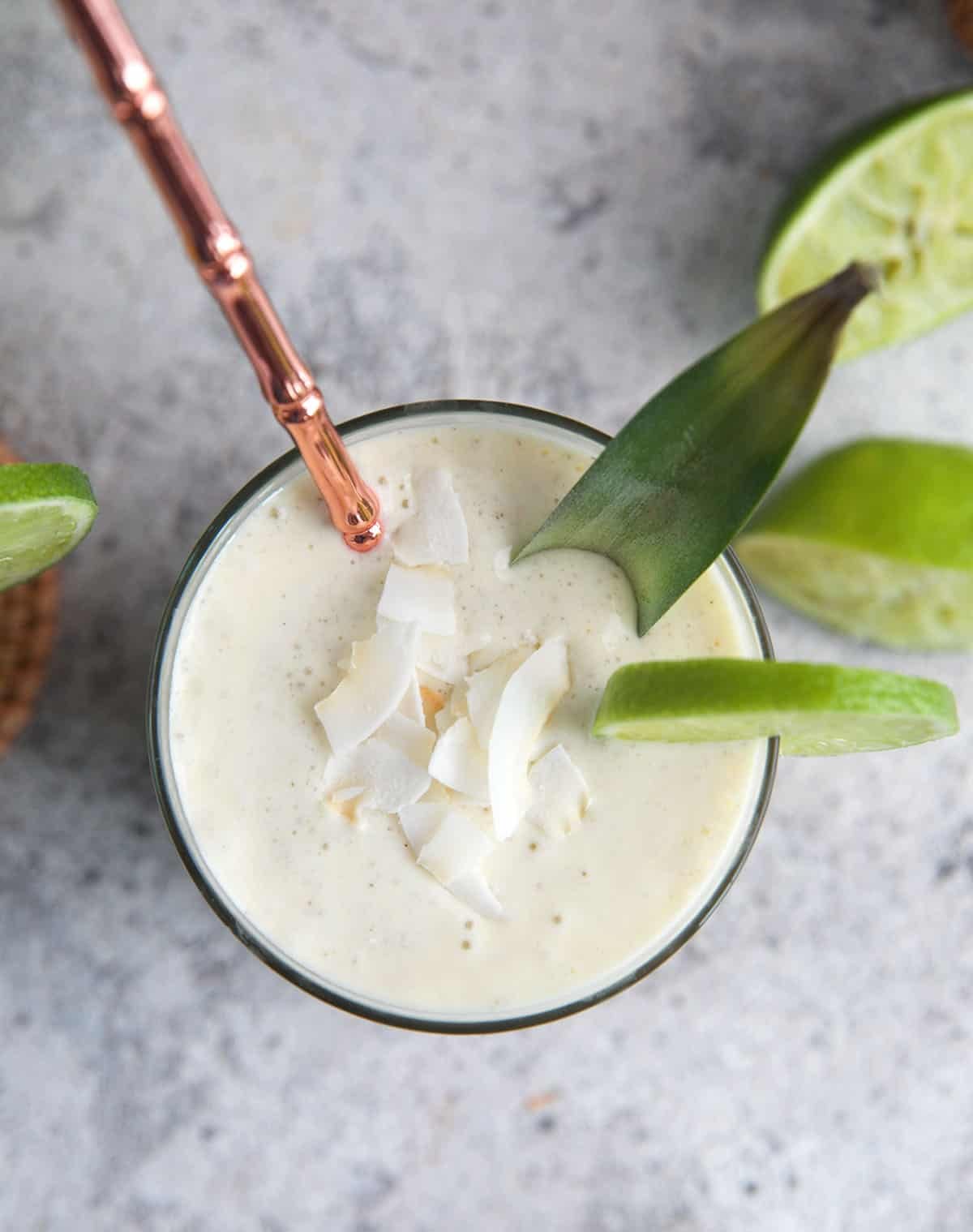 Pineapple smoothie topped with coconut flakes and a pineapple leaf.