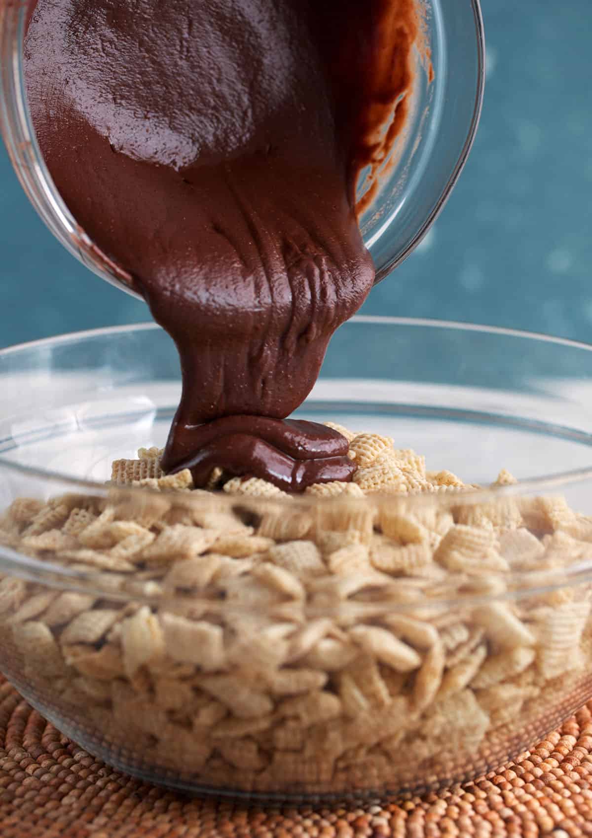 chocolate being poured over Chex cereal for muddy buddies
