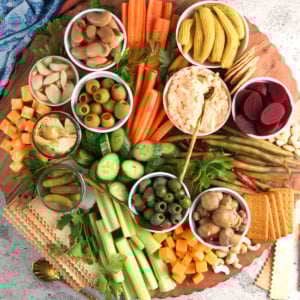 Classic Relish Tray served on a round lazy Susan type board with an assortment of vegetables , pickles, nuts and olives.
