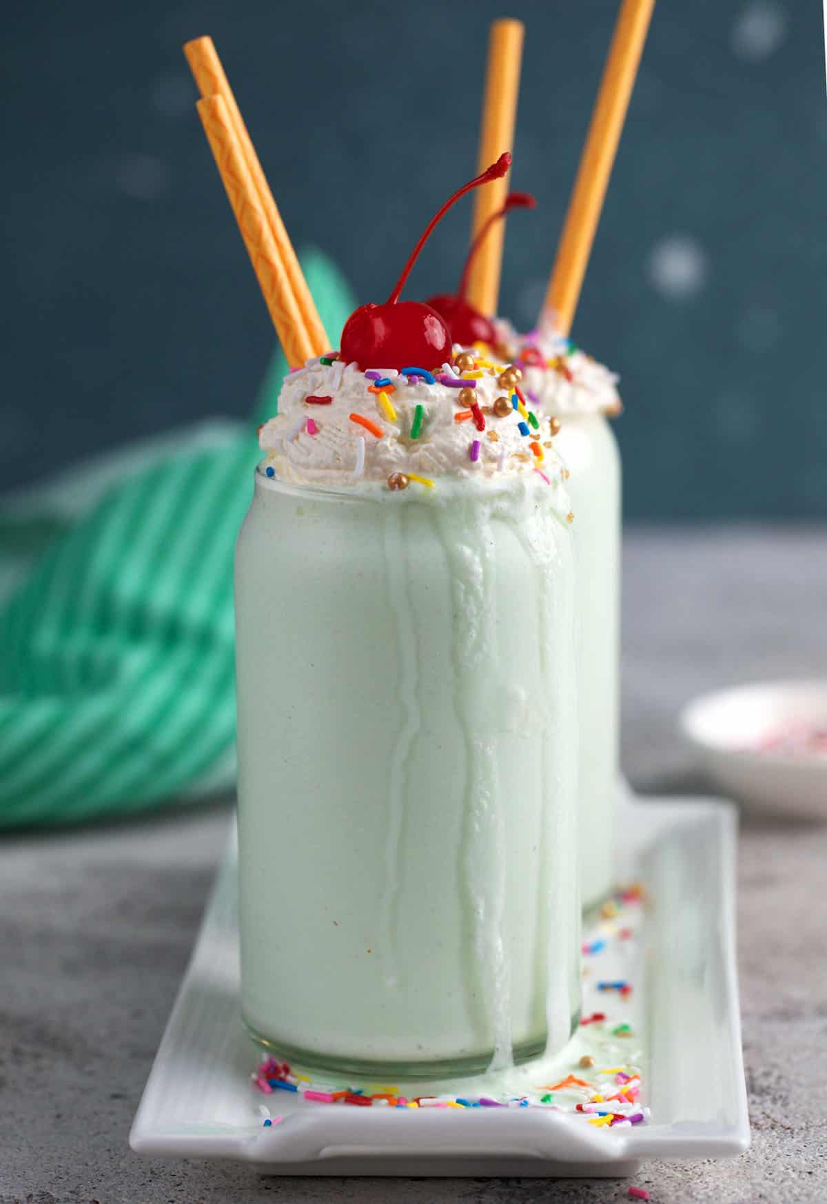Two shamrock shakes in glassed on a white porcelain tray.