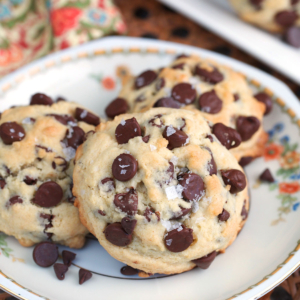 Sourdough Chocolate Chip cookies on a white plate with flowers and sprinkled with sea salt.