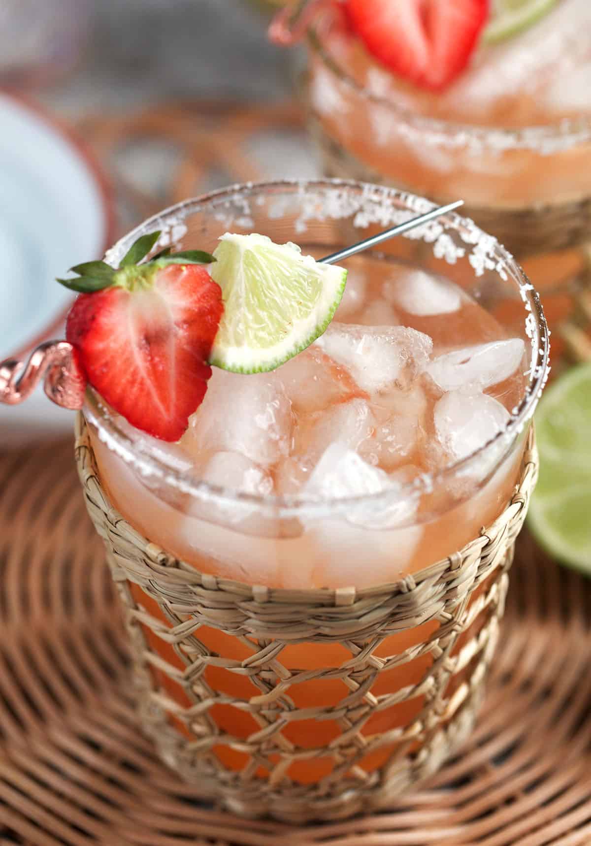 strawberry margarita recipe in a glass with a flamingo cocktail pick through a strawberry half and a lime wedge