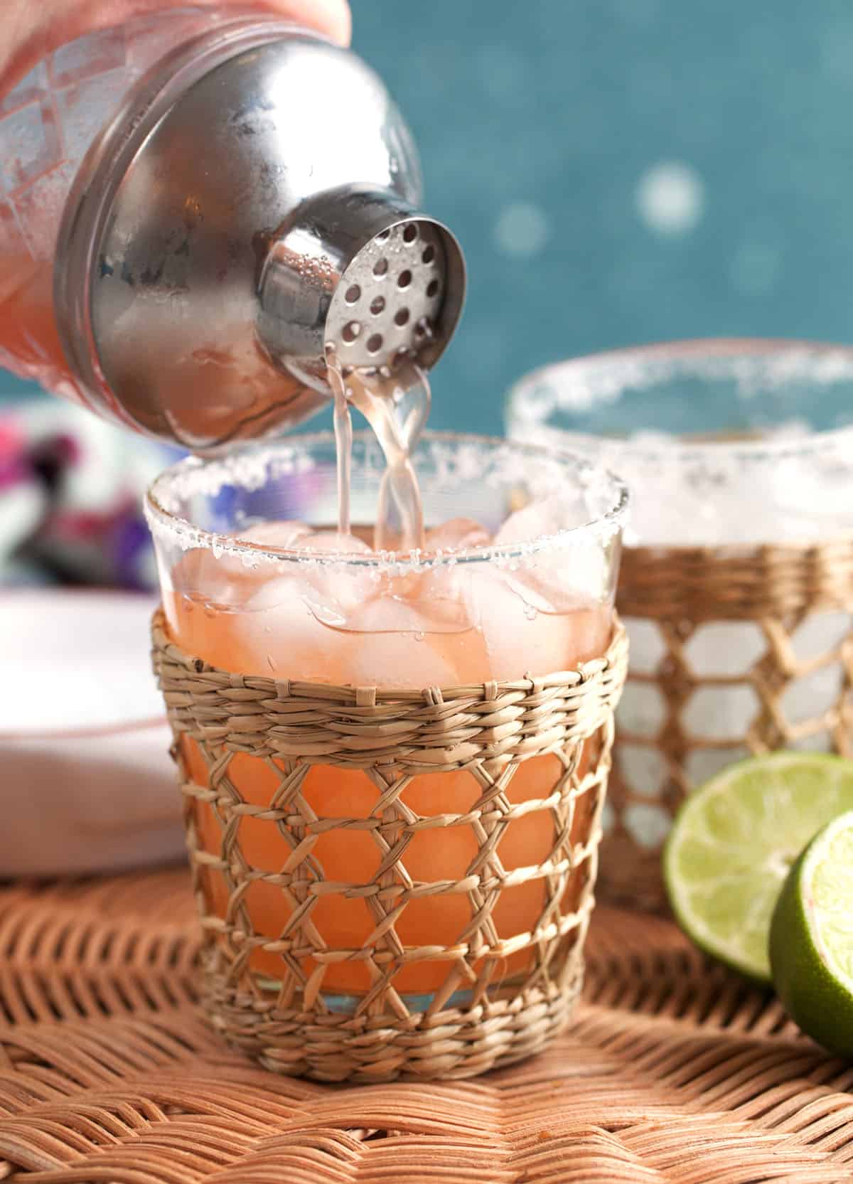 Strawberry Margarita being poured into a glass over the rocks with a cocktail shaker