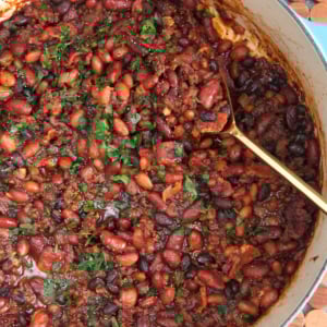 Cowboy beans in a large dutch oven with a gold serving spoon