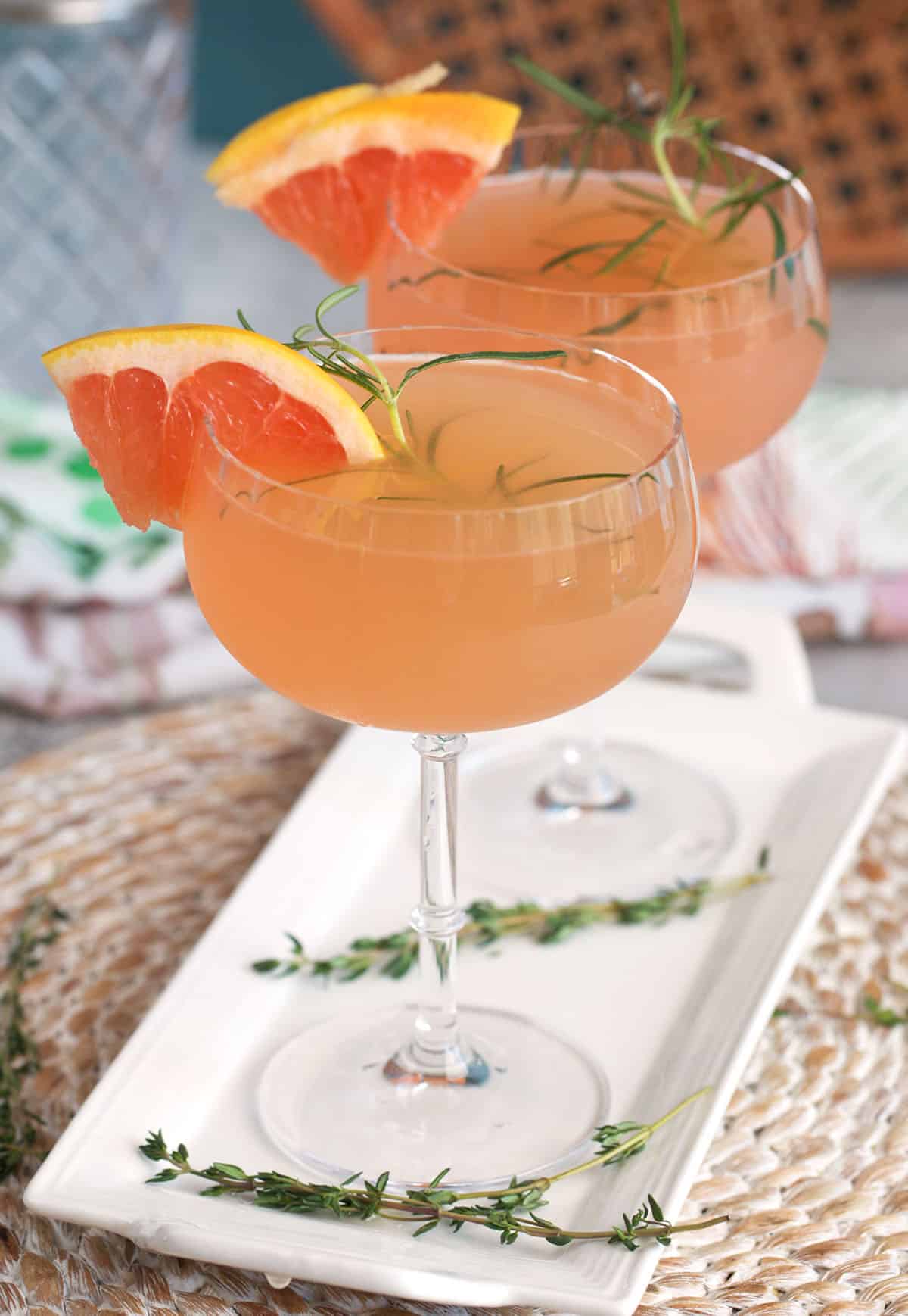 French Blonde Cocktail in a fluted coupe glass on a white platter with a thyme sprig