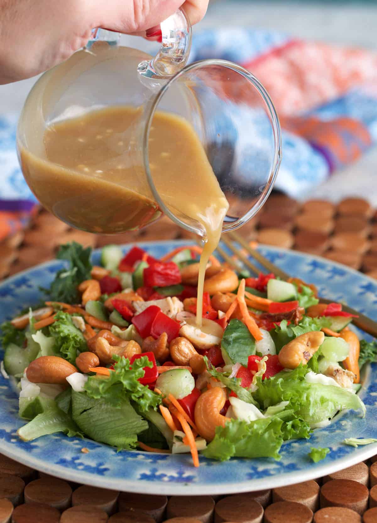 Miso salad dressing being poured over an asian inspired salad.