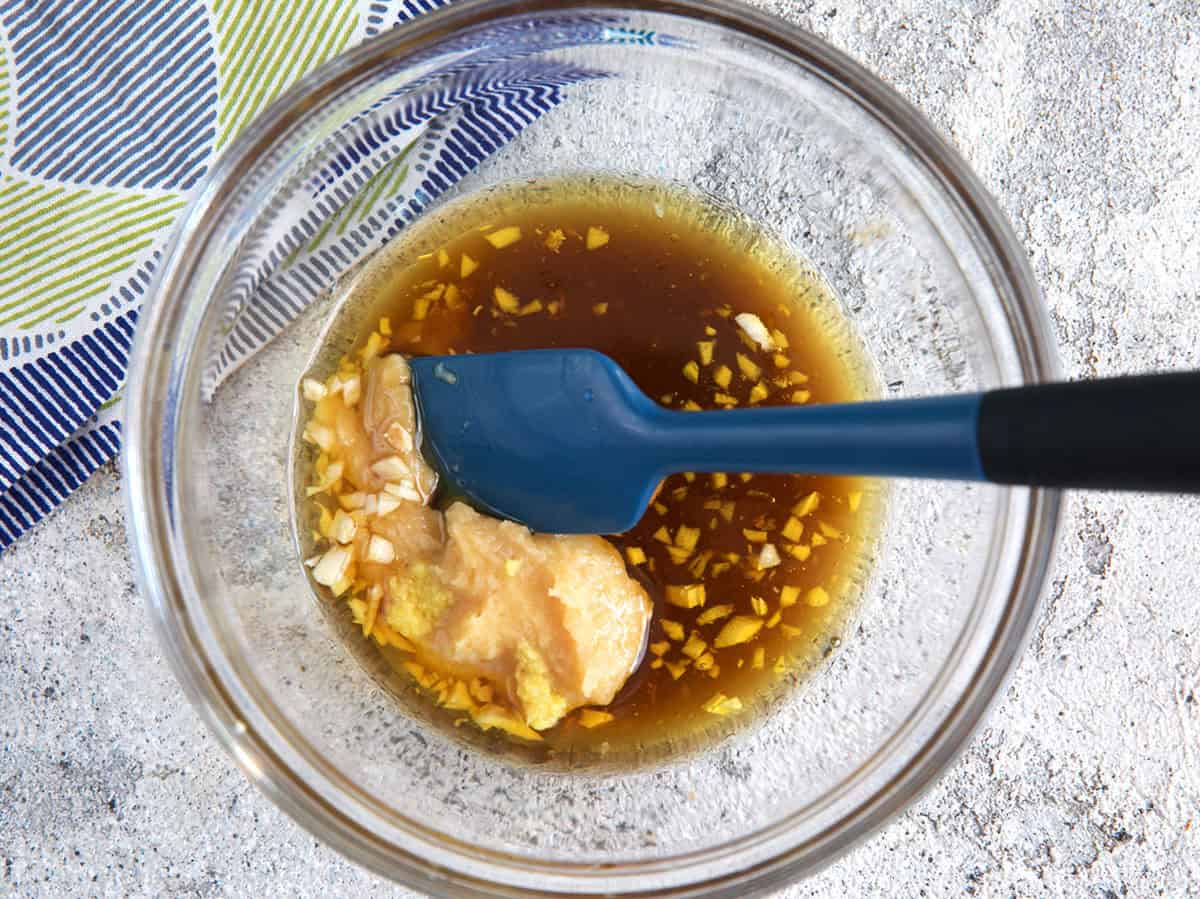 ingredients for miso dressing in glass bowl with a spatula