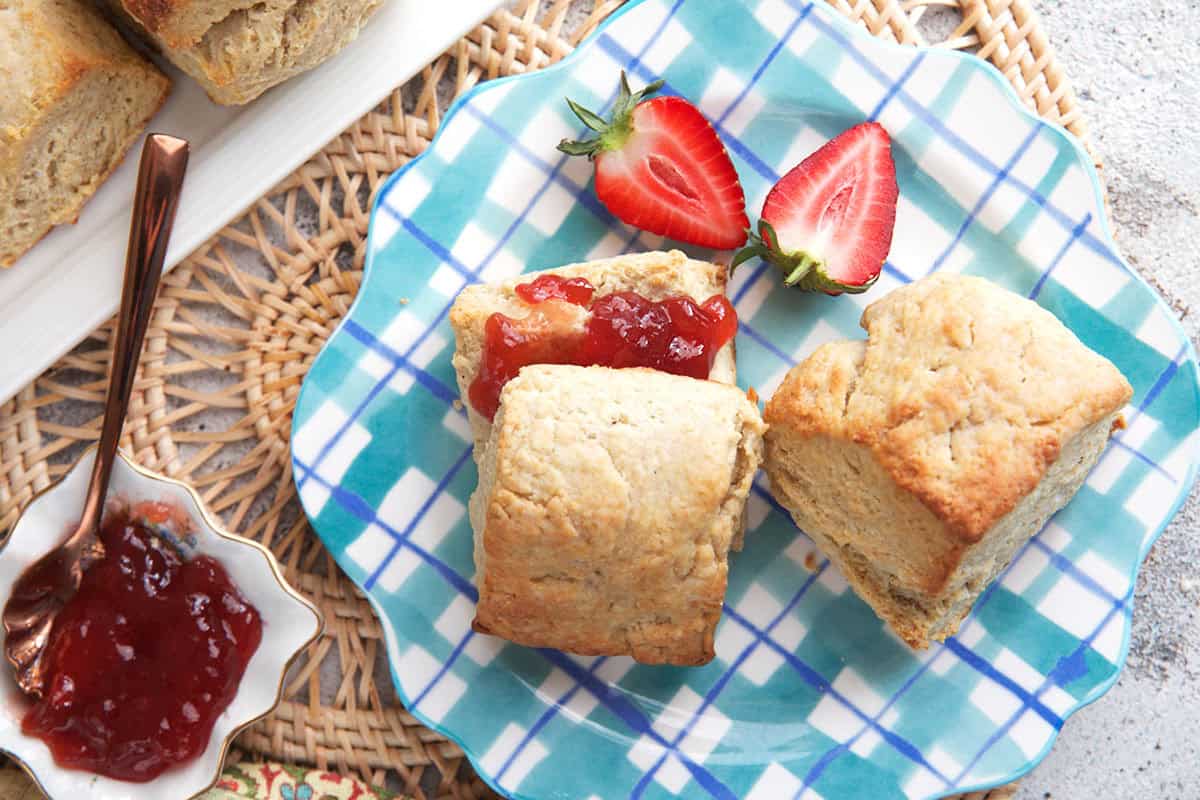 Sourdough biscuits on a blue plaid plate with a bowl of jam