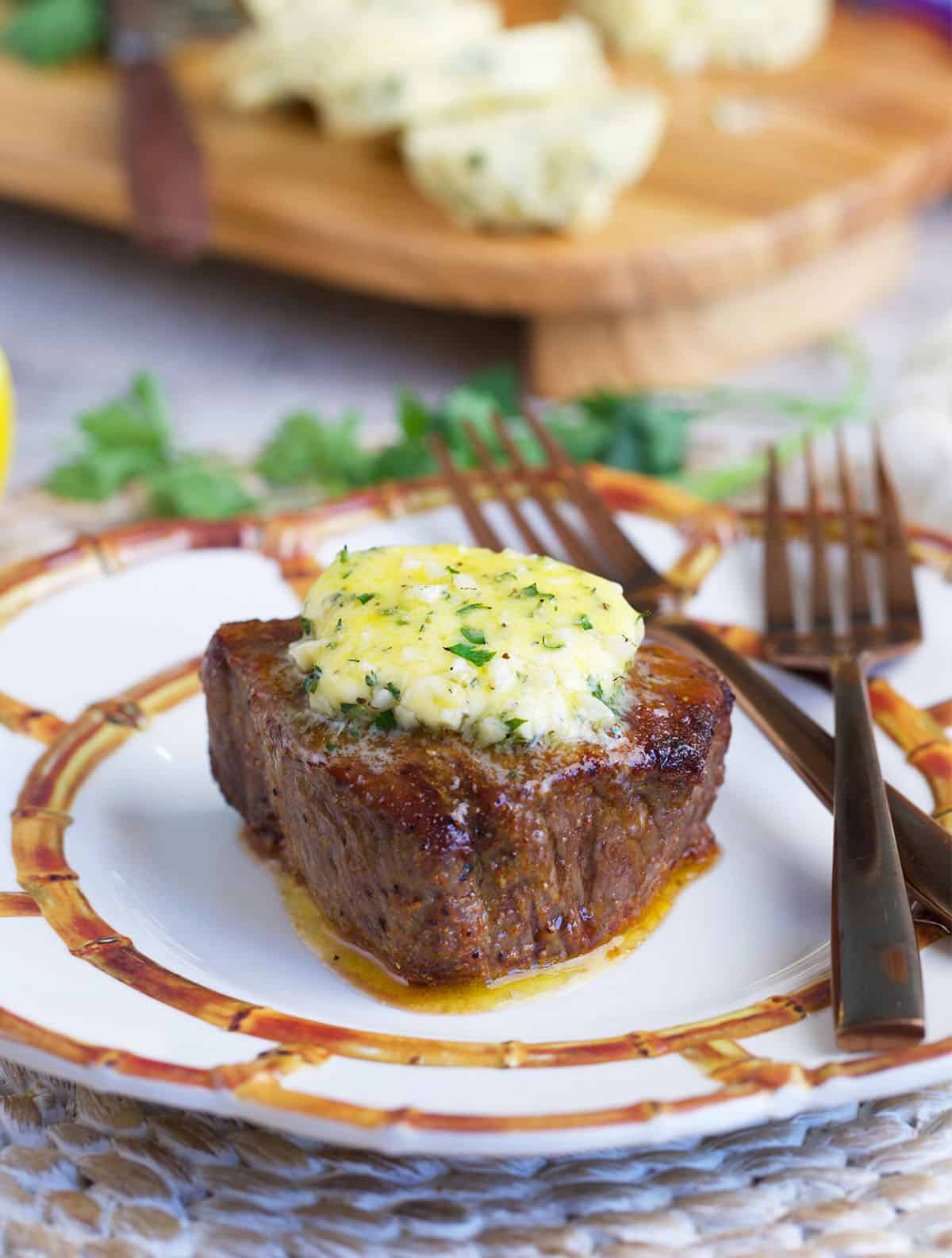 Air fryer sirloin steak topped with cowboy butter on a white plate
