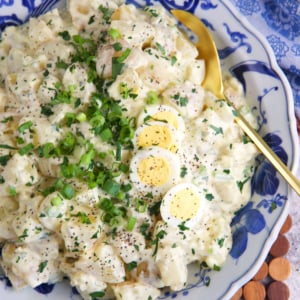 Amish potato salad in a blue and white serving bowl with a gold serving spoon