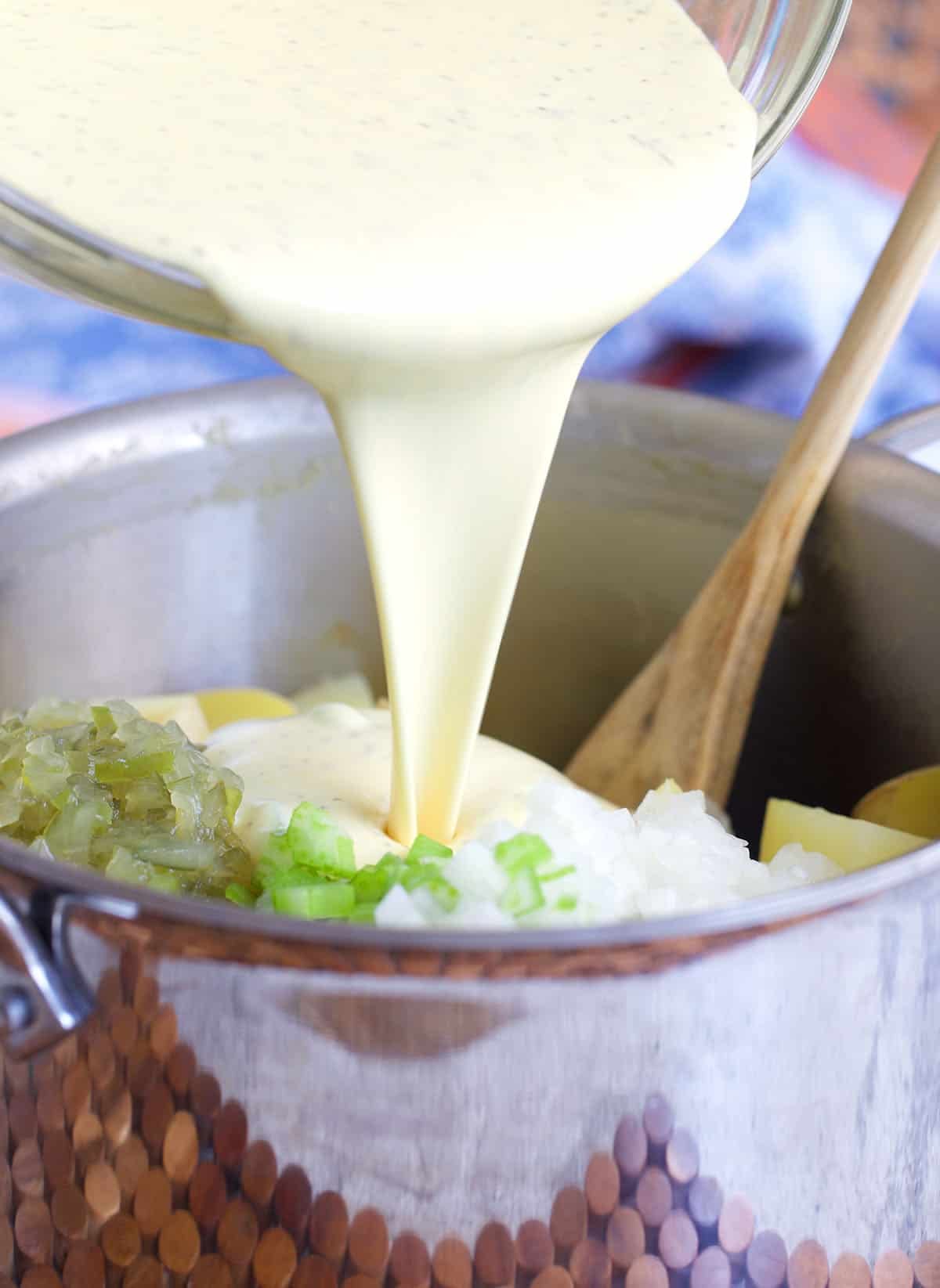 dressing being poured over ingredients for amish potato salad