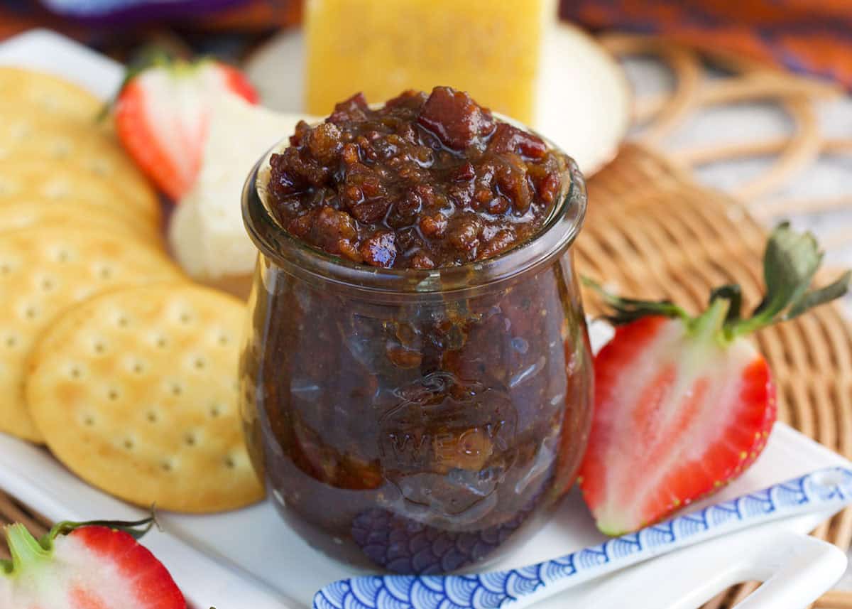 Bacon Bourbon Jam in a weck jar on a tray with crackers and strawberries.
