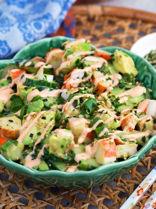 California Roll Cucumber Salad in a cabbage ware bowl on a wicker placemat.
