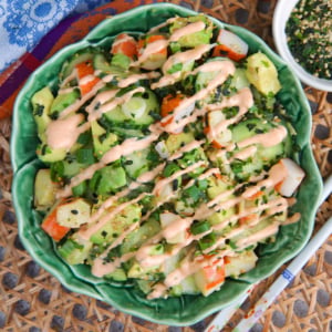 California Roll Cucumber Salad in a cabbage bowl with white chopsticks.