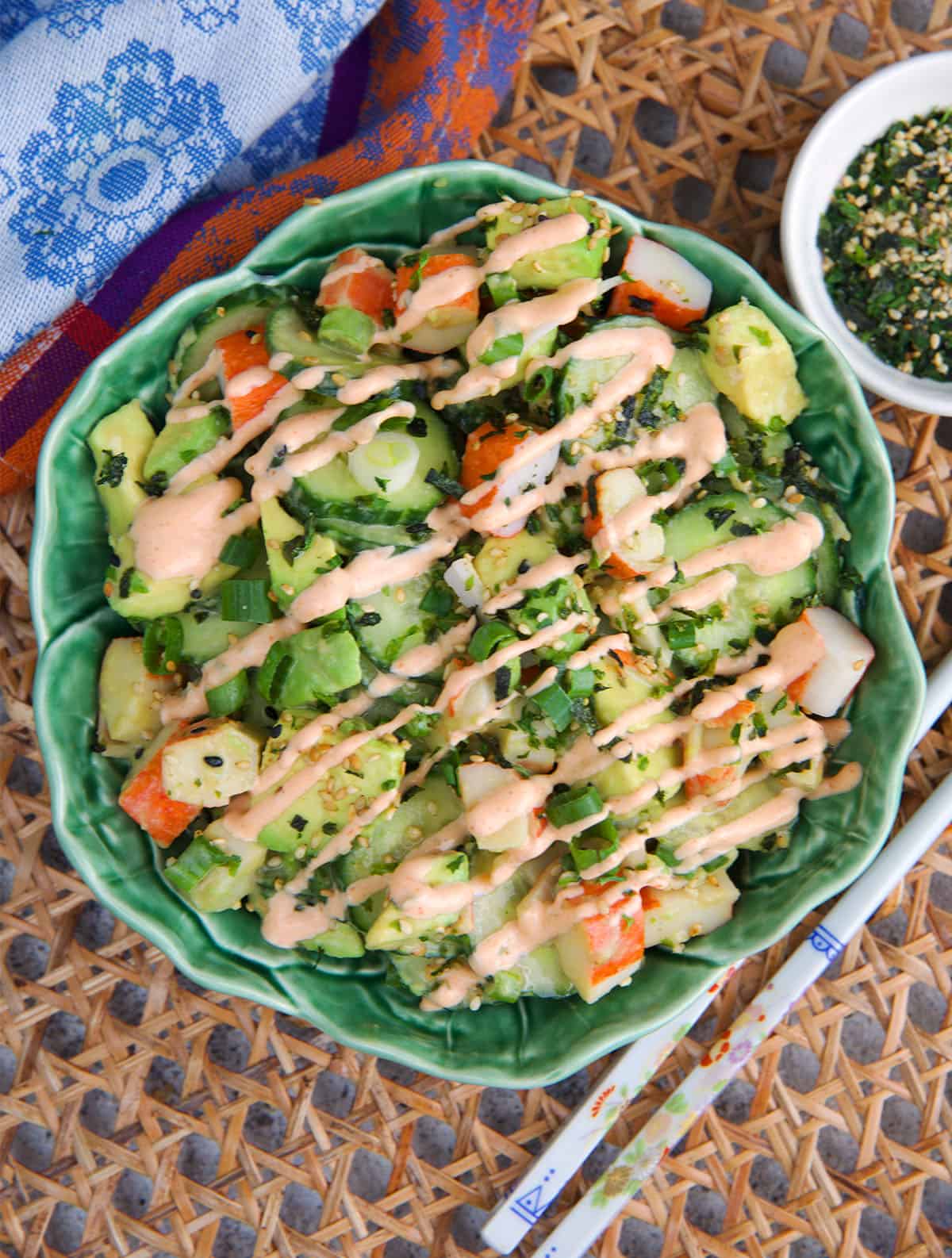 California Roll Cucumber Salad in a cabbage bowl with white chopsticks.