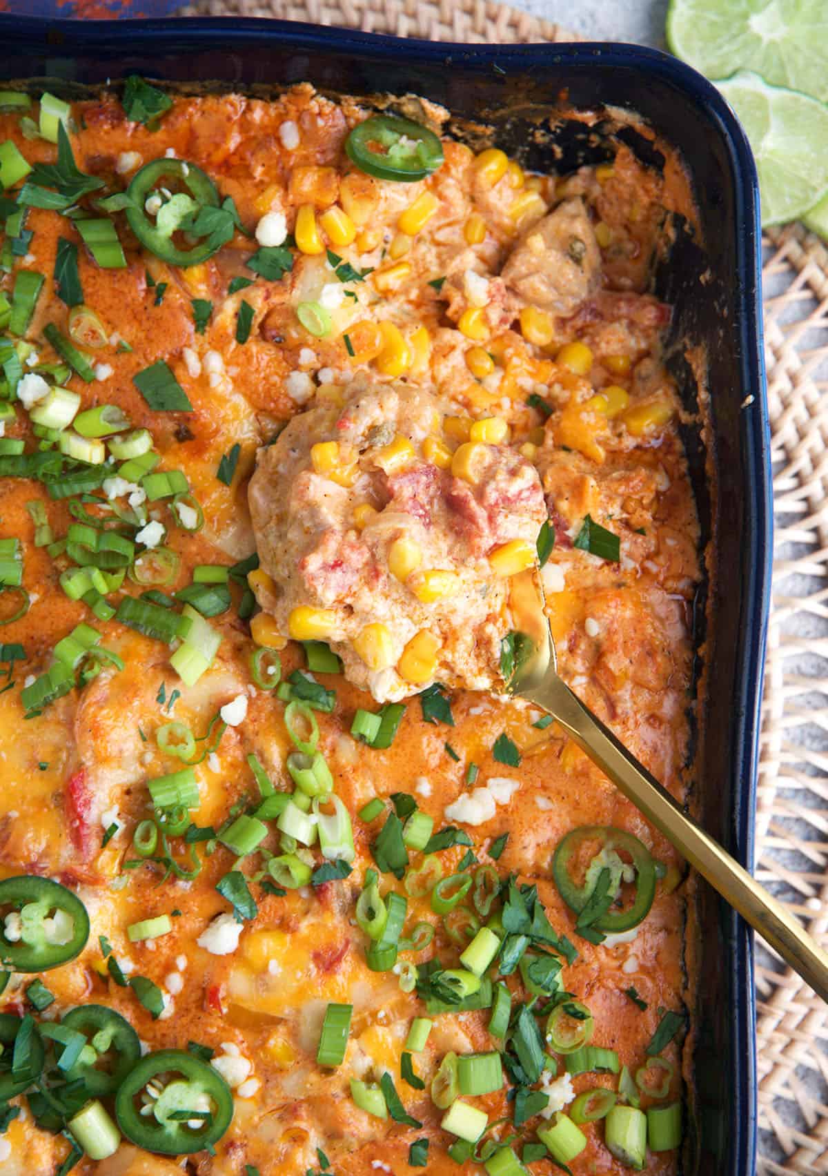 Chicken Fajita Casserole in a blue casserole dish with a gold spoon.