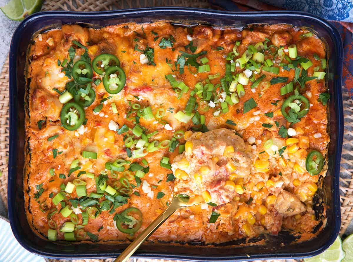 Chicken Fajita Casserole in a casserole dish, topped with sliced jalapeño and green onion with a gold serving spoon