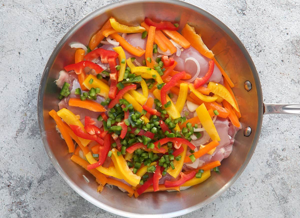 chicken thighs, bell peppers and jalapeño in a skillet