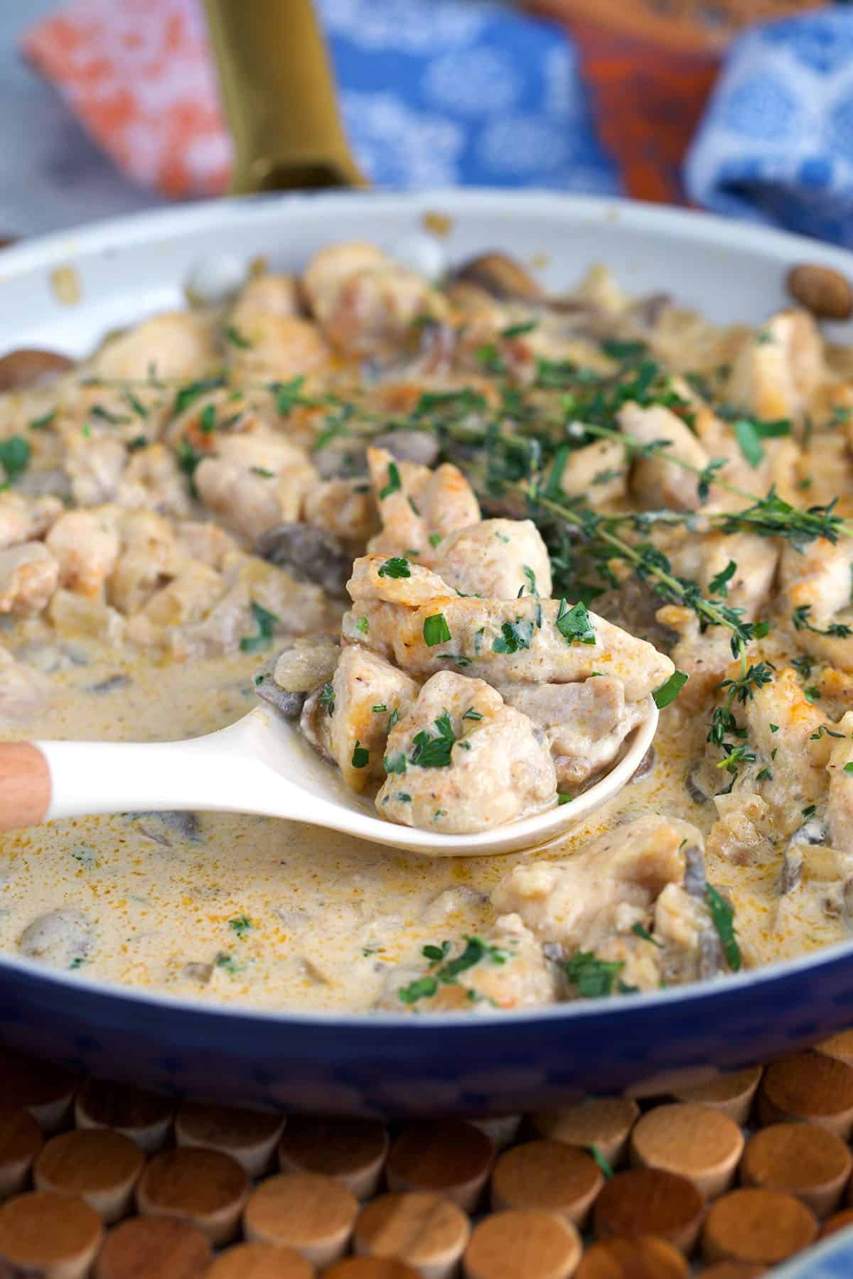 Chicken stroganoff being served with a wooden and silicone spoon.