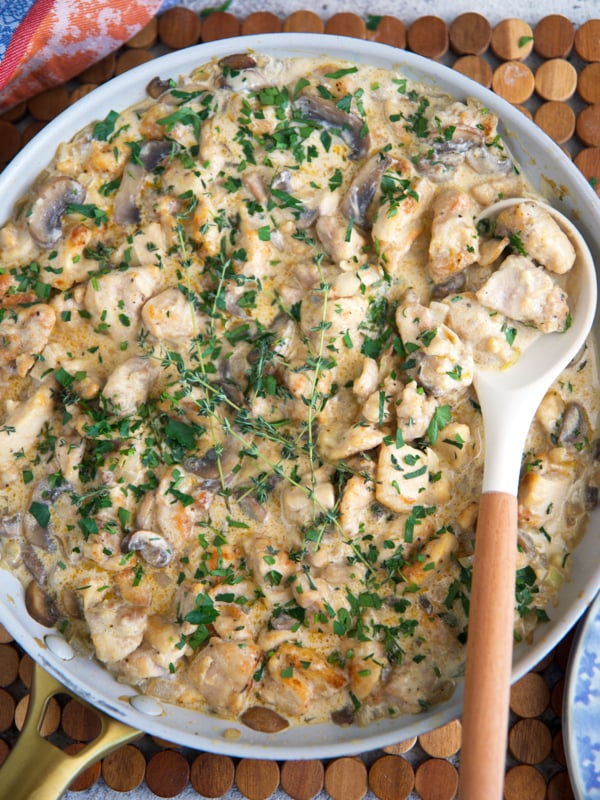 Chicken stroganoff recipe in a large skillet with a wooden spoon for serving.