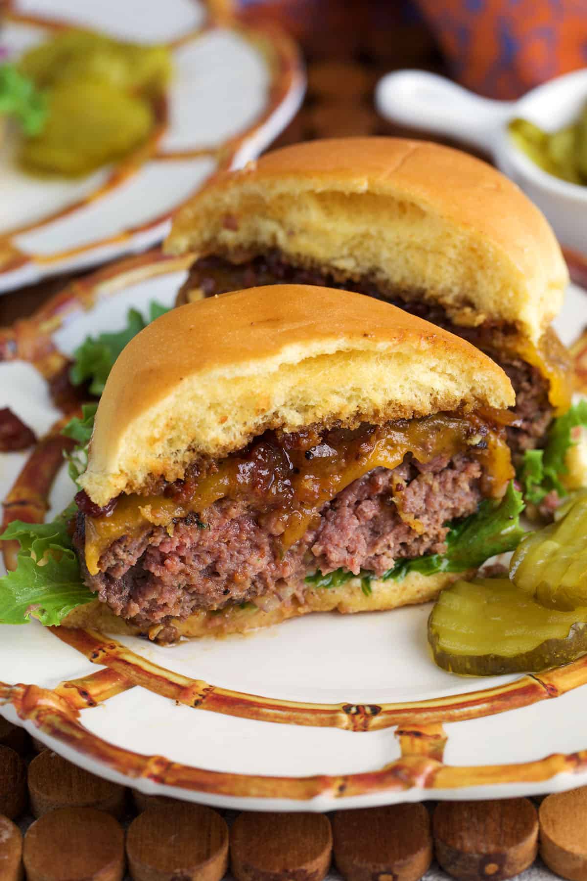 Ranch Crack Burger cut in half on a white plate with pickles on the side.