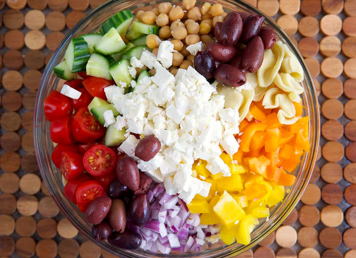 Ingredients for greek tortellini salad in a mixing bowl.