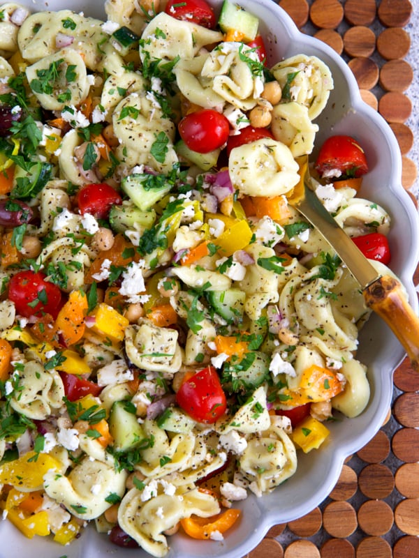 Greek Tortellini Pasta Salad in a fluted white serving bowl