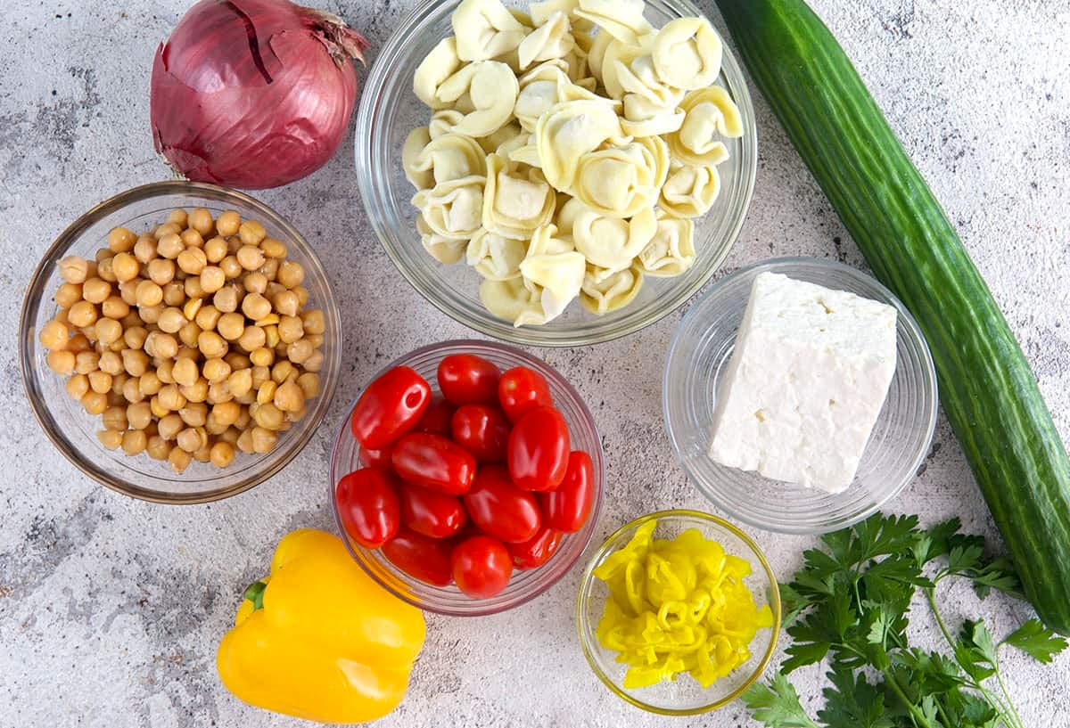 Greek Tortellini Salad ingredients, chickpeas, tortellini, feta, cucumbers and veggies.