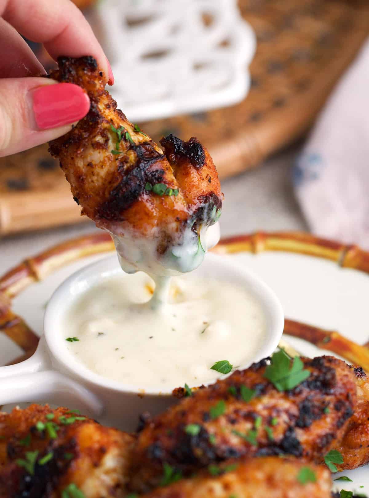 Grilled chicken wing being dipped in ranch dressing