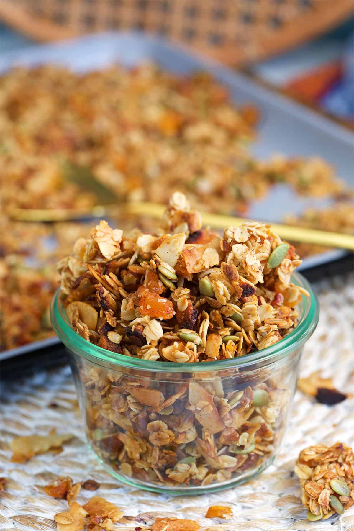 Homemade granola in a weck jar with a baking sheet in the background with granola on it.