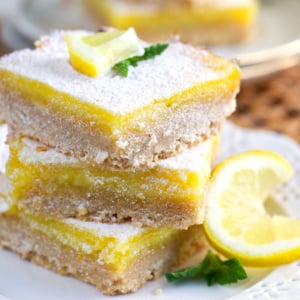 Lemon Bars stacked on a white plate and dusted with powdered sugar.
